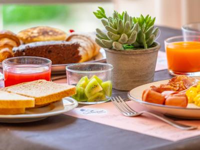 Colazione con pane, kiwi, succhi e pianta decorativa.