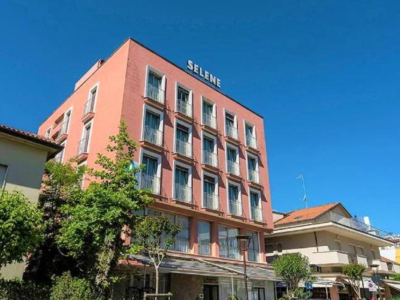 Edificio rosa a più piani con insegna Selene e cielo blu.