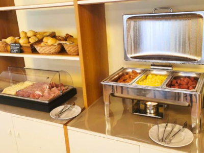 Buffet con pane, formaggi, affettati e piatti caldi.