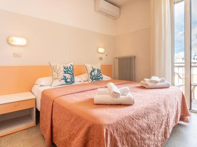 Camera accogliente con letto matrimoniale, cuscini decorati, asciugamani e balcone.