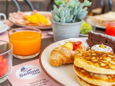 Colazione con croissant, pancake, succo d'arancia e torta al cioccolato.