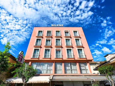 Edificio rosa con finestre e cielo blu, insegna 'Selene'.
