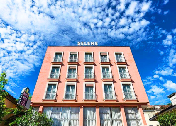 Edificio rosa con finestre e cielo blu, insegna 'SELENE'.
