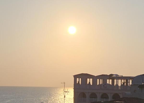 Tramonto sul mare con edifici in silhouette.