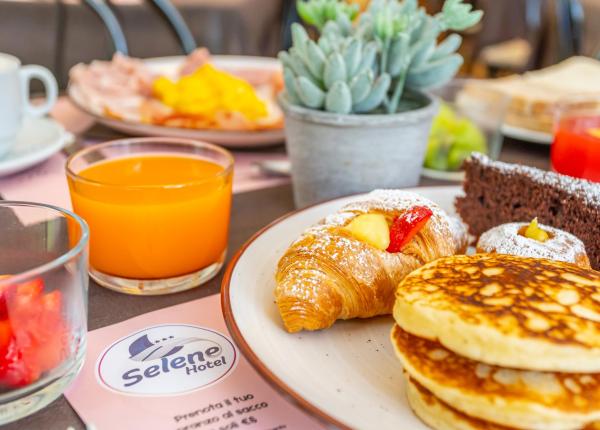 Colazione con croissant, pancake, succo e dolci al Selene Hotel.