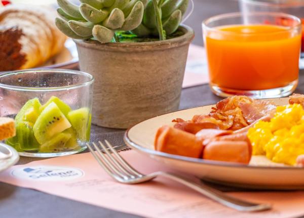 Colazione con succo, uova, pane, kiwi e dolci.