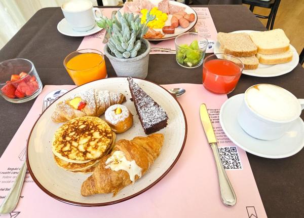 Colazione ricca con dolci, frutta e bevande.