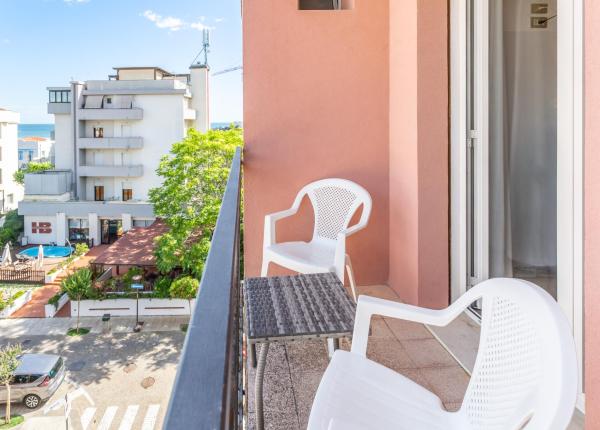 Balcone con sedie bianche e vista mare.