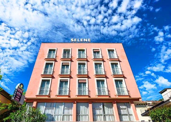 Edificio rosa con finestre e cielo blu, insegna 'Selene'.