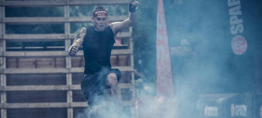 Atleta salta sopra il fuoco durante una gara di resistenza.
