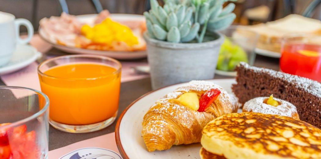Colazione con croissant, succo d'arancia, pancake e dolce al cioccolato.