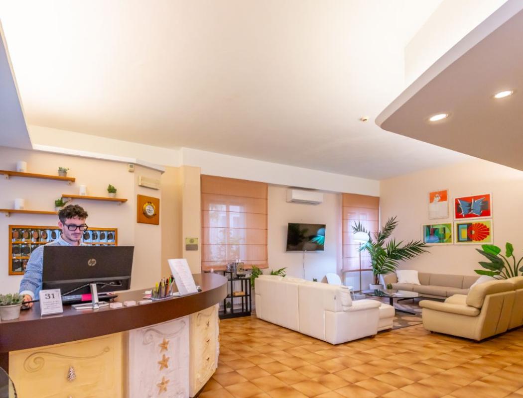 Reception di un hotel con divani e piante, arredamento accogliente e moderno.
