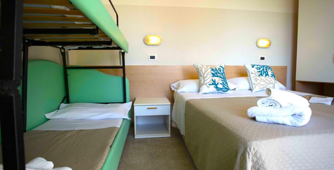Camera con letto matrimoniale e letti a castello, decorata con cuscini e asciugamani.