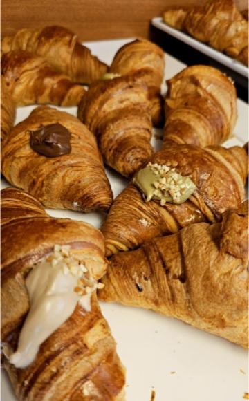Croissant ripieni con creme al cioccolato, pistacchio e nocciola, decorati con granella.
