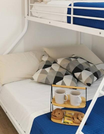 Letto a castello con cuscini geometrici e vassoio con tazze e biscotti.
