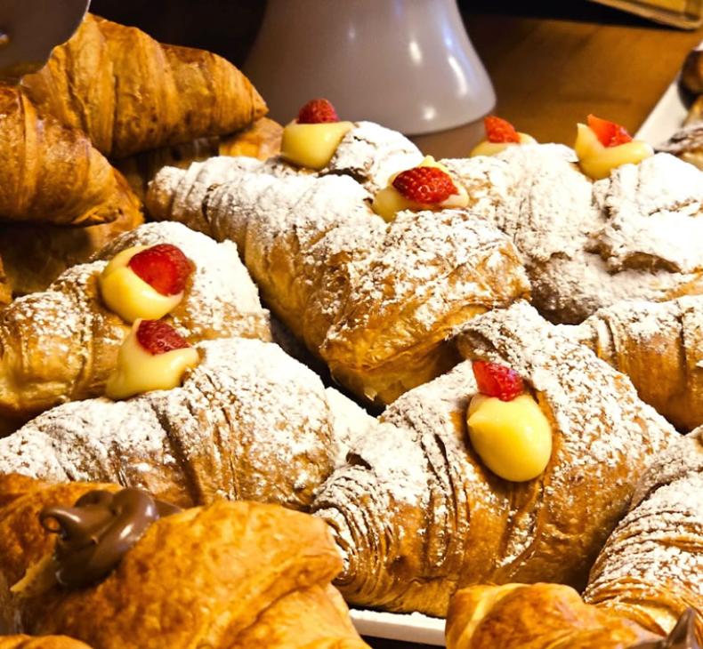Croissant al cioccolato e crema, decorati con fragole e zucchero a velo.