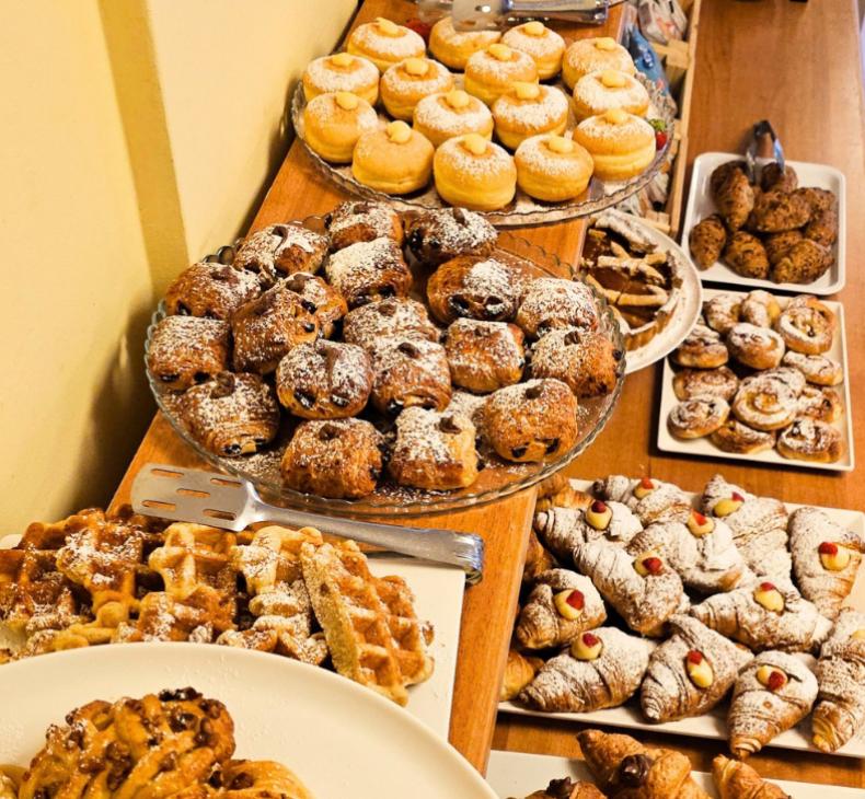 Buffet di dolci assortiti con croissant, biscotti e pasticcini spolverati di zucchero a velo.