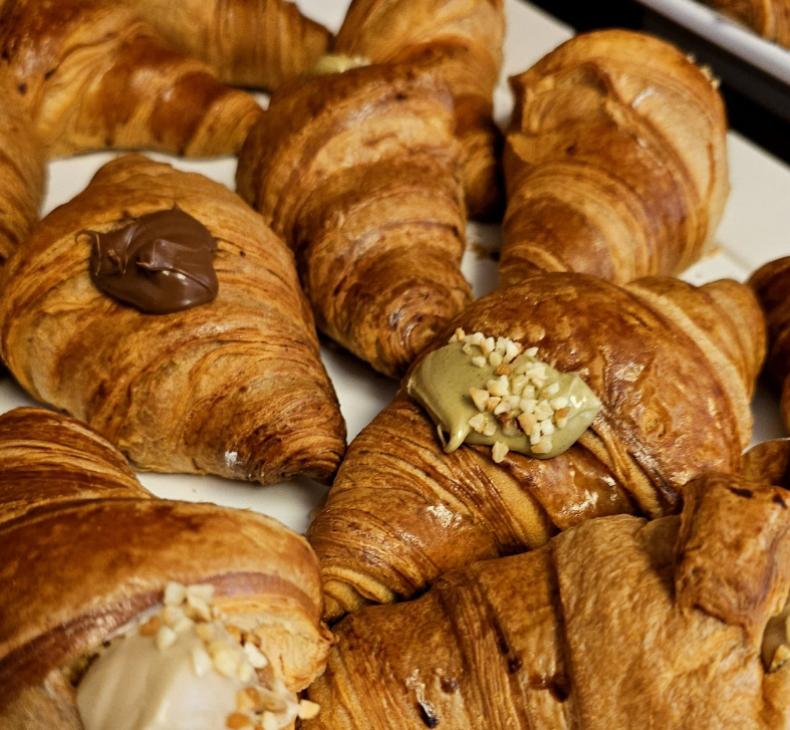 Croissant con crema al cioccolato e pistacchio, guarniti con granella di nocciole.