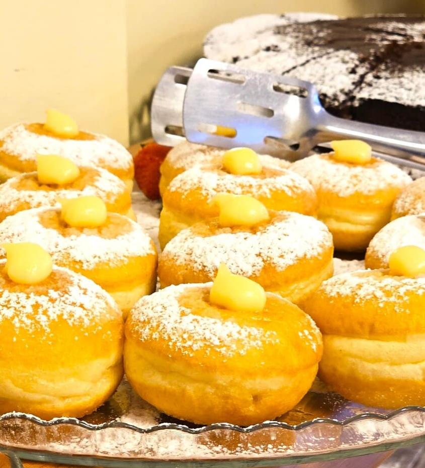 Dolci con crema e zucchero a velo, accanto a una torta al cioccolato.