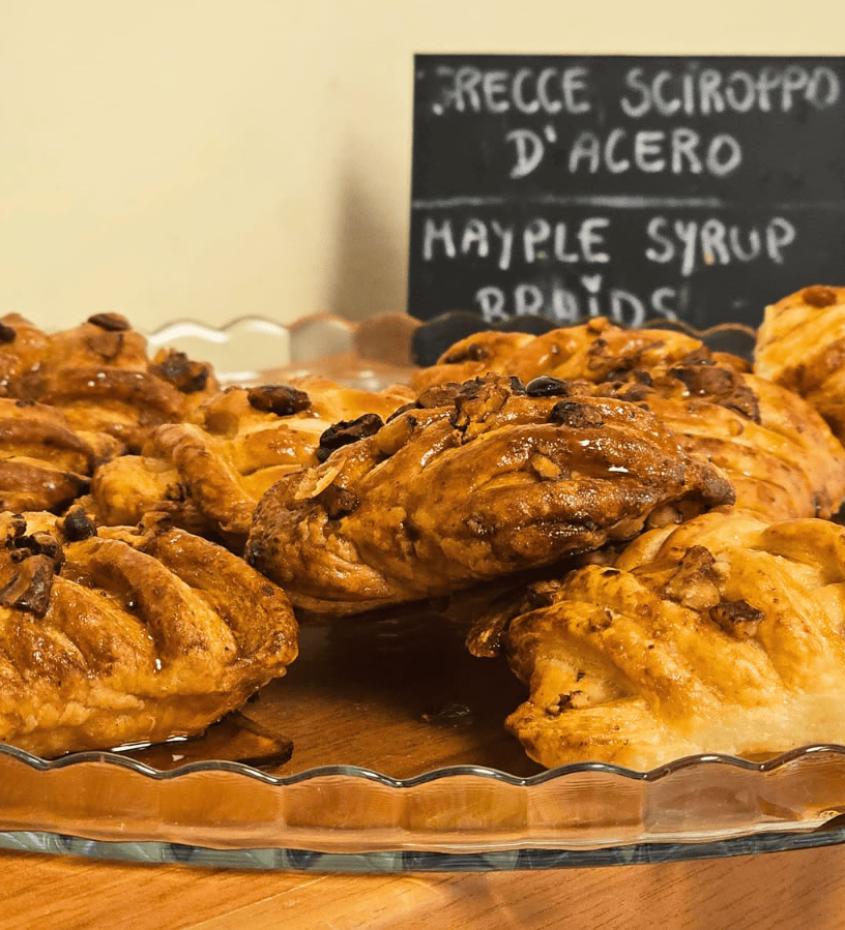 Treccine al sciroppo d'acero su piatto di vetro, con cartello descrittivo.