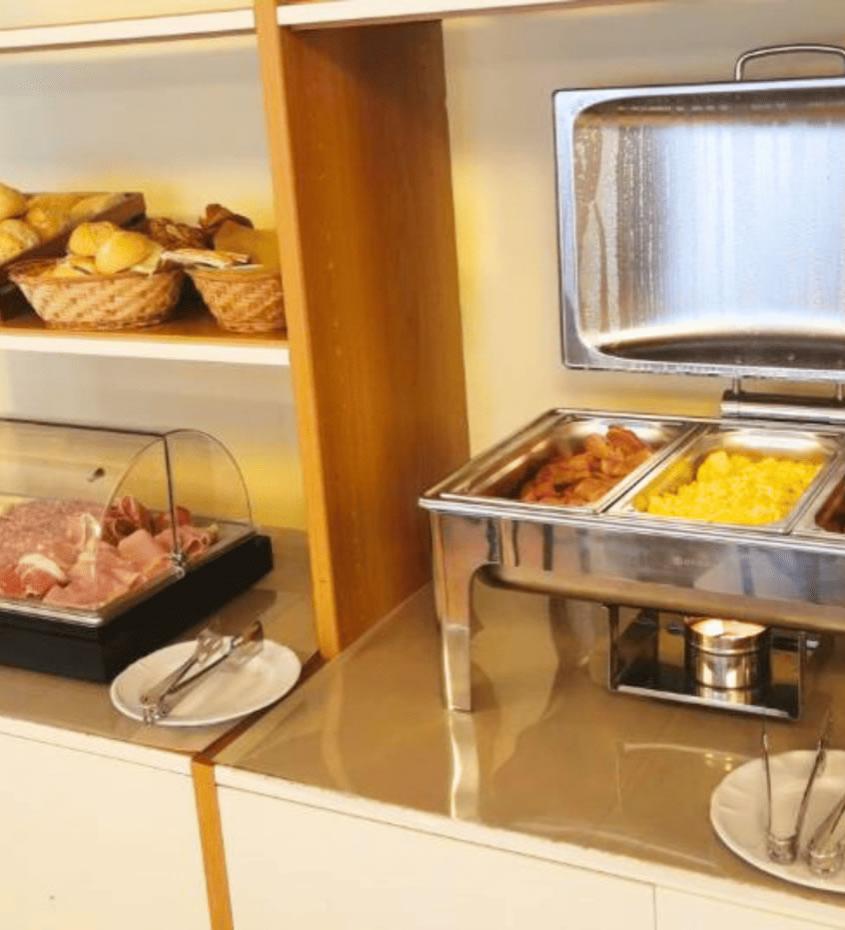 Buffet con pane, salumi, formaggi, uova strapazzate, salsicce e pancetta.