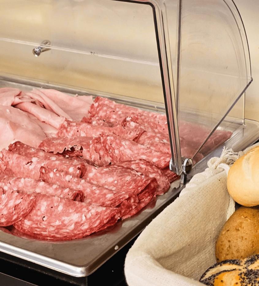 Affettati e formaggi sotto campana, con pane assortito accanto.